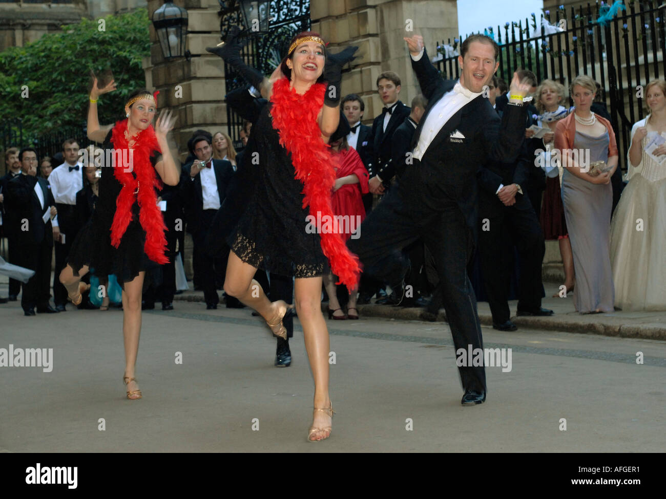 Les participants à la Clare College peut Ball sont divertis par les danseurs lors de l'attente pour entrer la balle. Banque D'Images