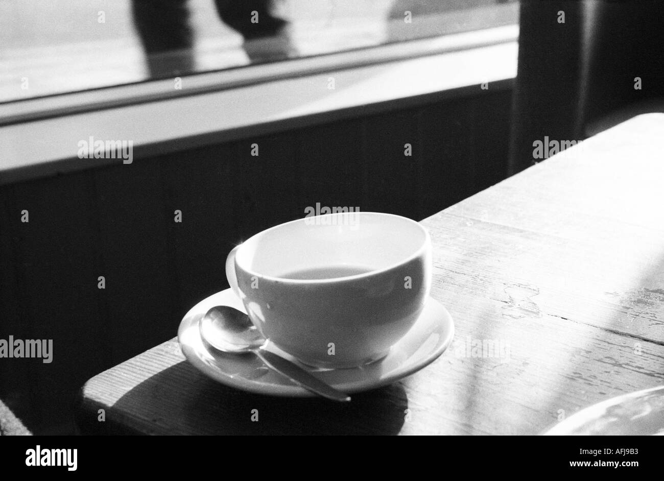 Tasse et soucoupe sur la table à café avec personne qui marche par l'extérieur Banque D'Images