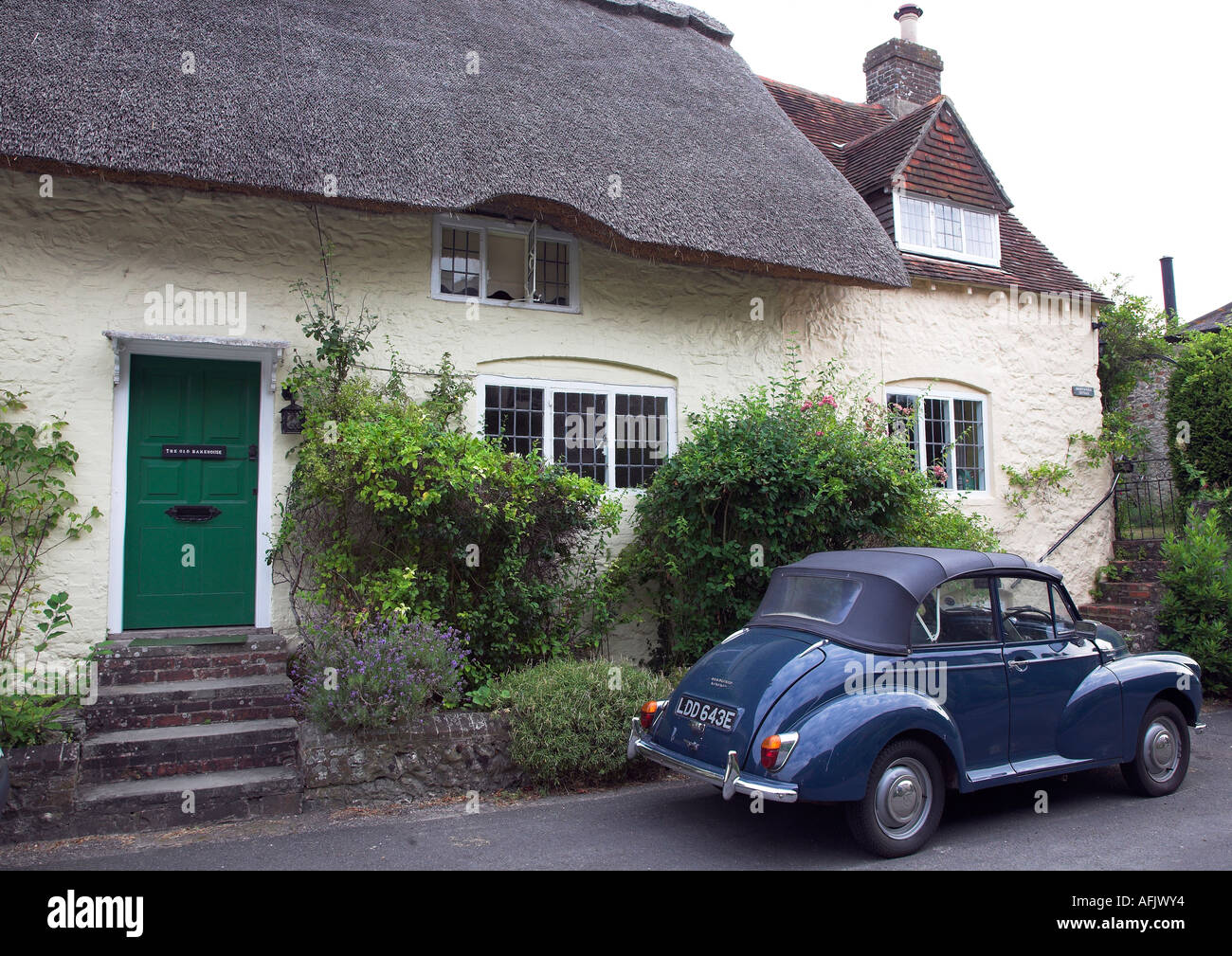 Pays traditionnel thatched cottage dans le village de Amberley Sussex de l'Ouest avec vintage Morris 1000 voiture garée à l'extérieur. 2006 Banque D'Images