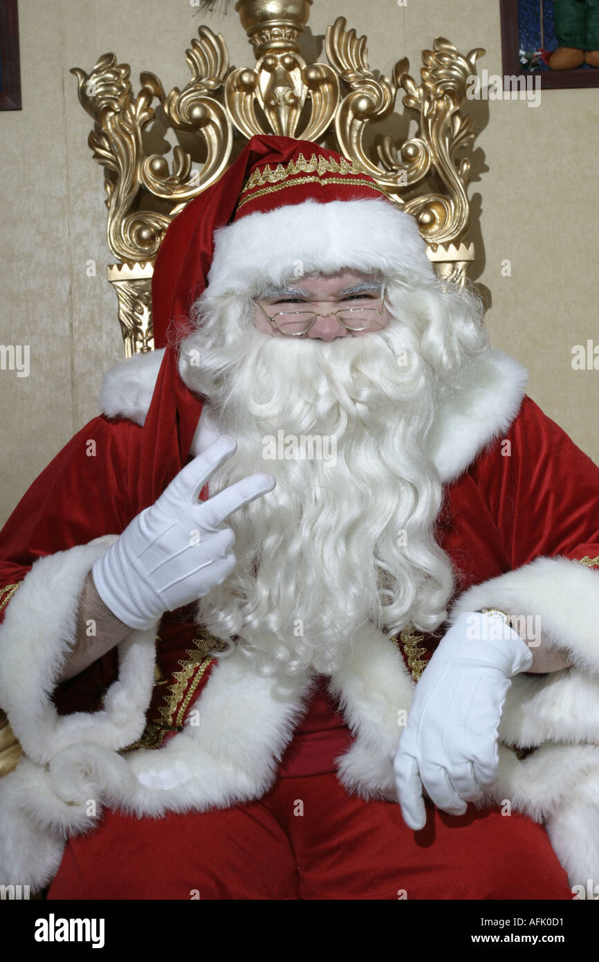 Nasty le Père Noël dans sa grotte avec 2 deux doigts vers le haut sur son trône Banque D'Images