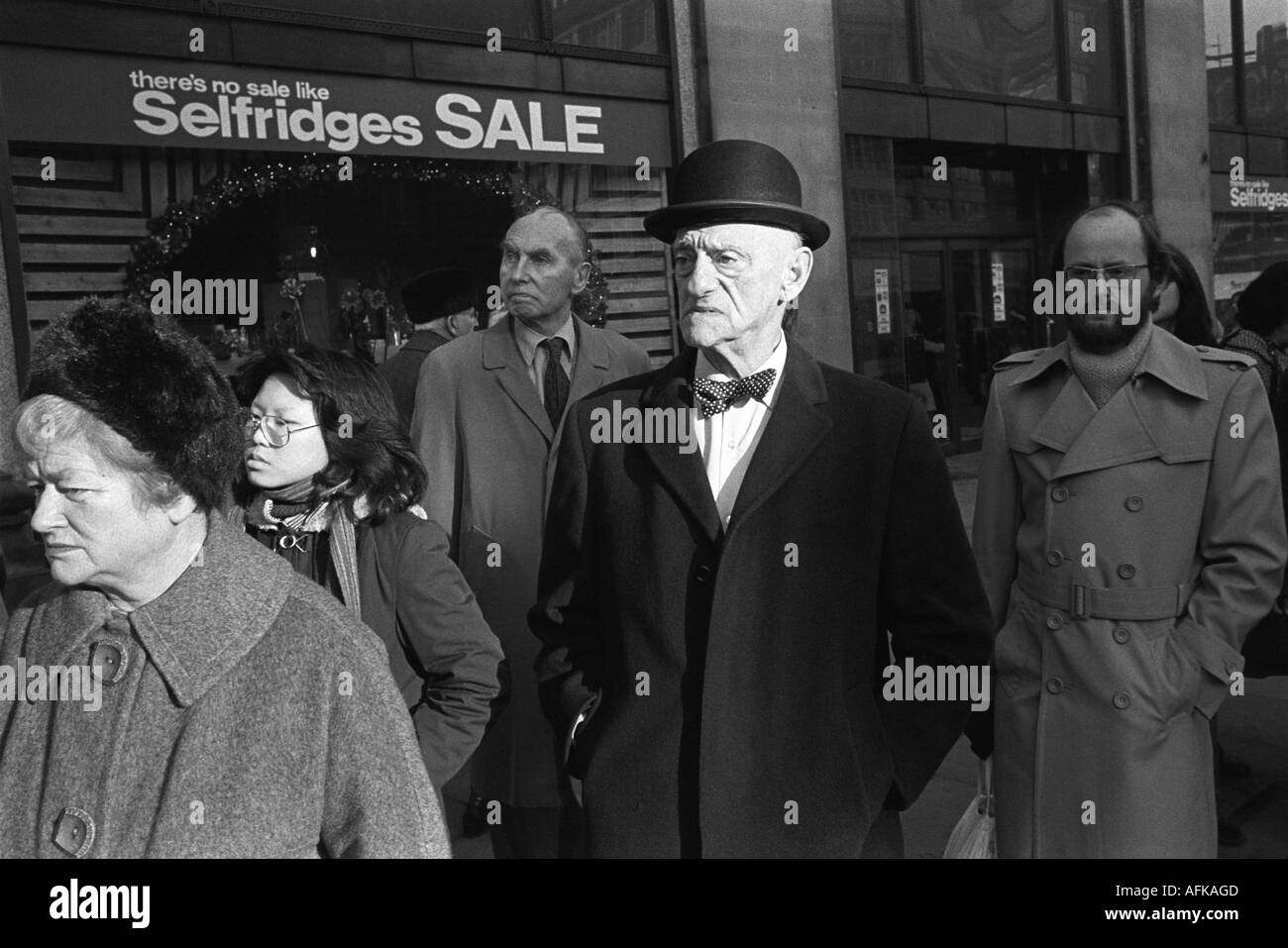 Homme en chapeau melon et noeud papillon attendant dans une file d'attente de bus Oxford Street à l'extérieur de Selfridges. Premier jour des ventes du nouvel an 1976 HOMER SYKES Banque D'Images