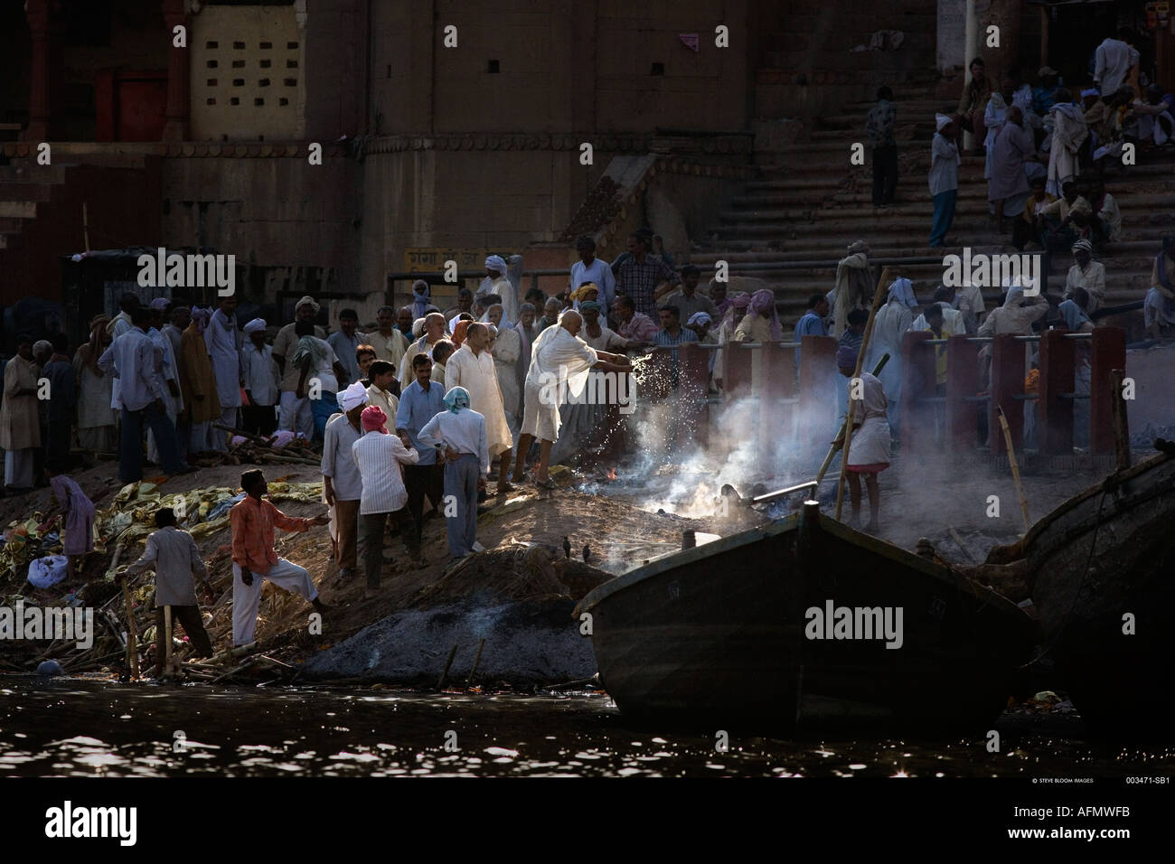 Verser de l'eau du Gange sacré sur les cendres dans la crémation site sur les rives du Gange, Varanasi Inde Banque D'Images