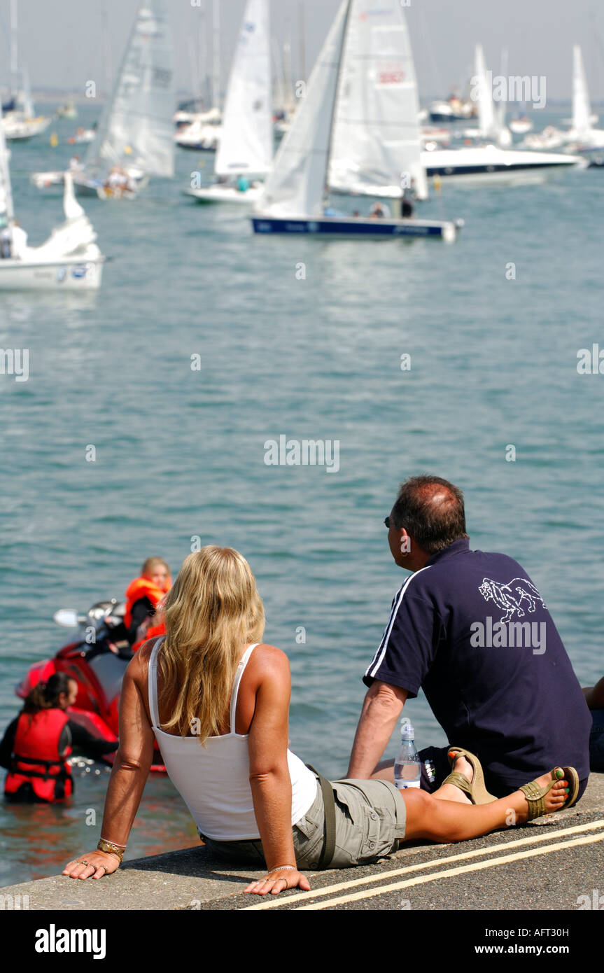 Les jeunes met la femme couple regardant le yacht racing au cours de la semaine de Cowes en été sur l'île de Wight Banque D'Images