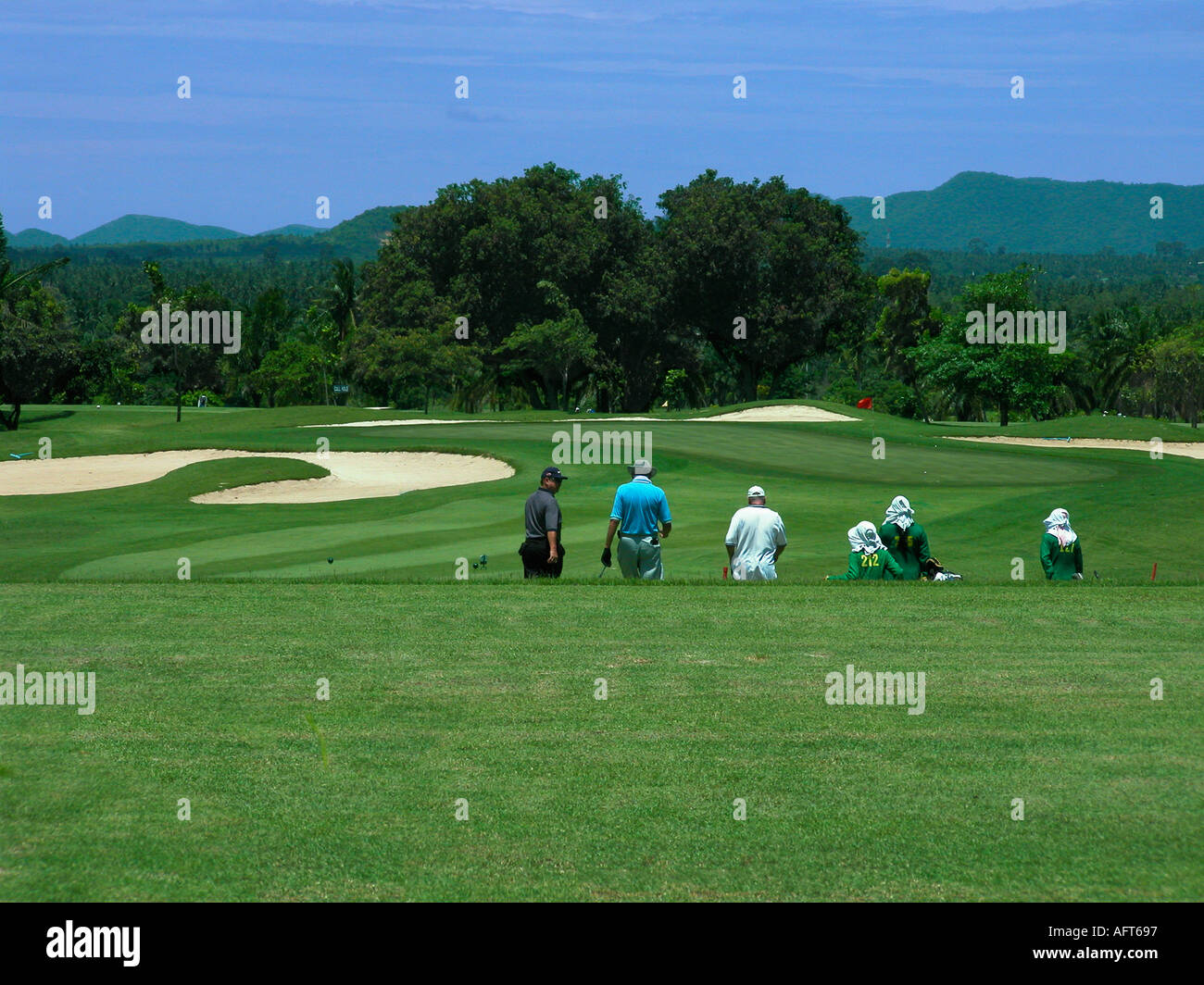 3 golfeurs et 3 caddies vu de derrière la marche au trou suivant,d à Phoenix Golf and Country Club Pattaya Thaïlande Banque D'Images