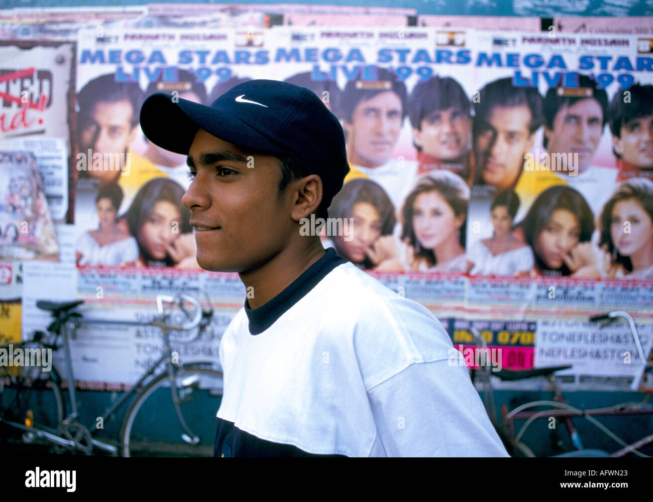 L'adolescent de BAME des années 1990 porte une casquette de baseball Nike  avec des affiches de star de film Bollywood sur le mur derrière. Brick Lane  Londres UK HOMER SYKES Photo Stock -
