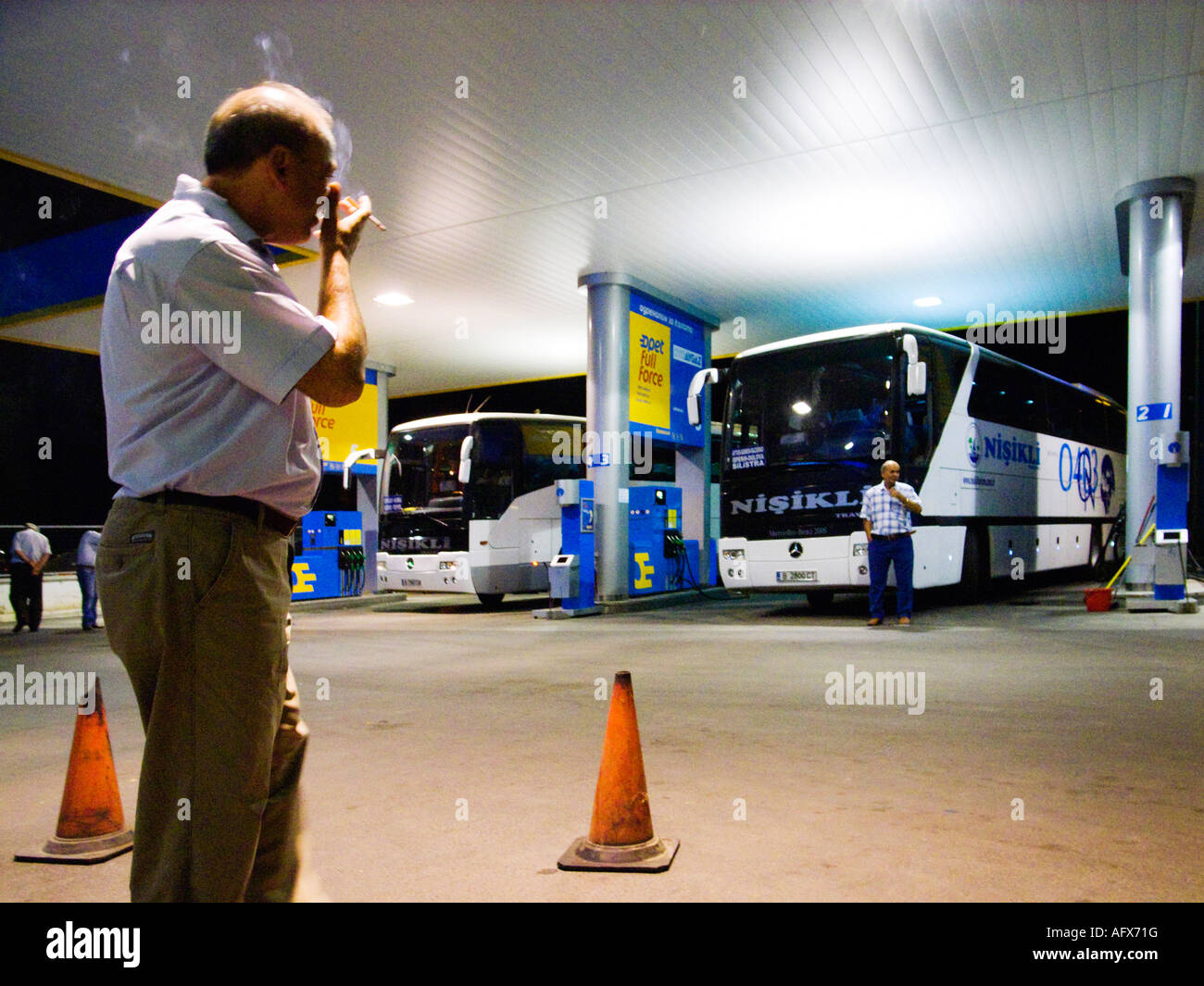 Chauffeur de bus de longue distance prenant un court séjour et de fumer une cigarette, tard dans la nuit à la station-service, Edrine, Turquie Banque D'Images