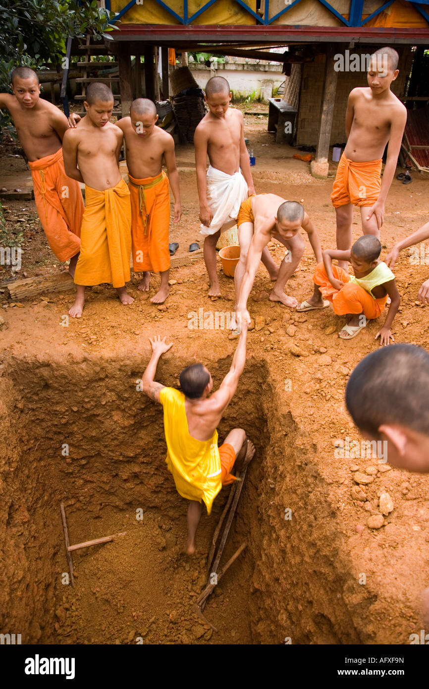 Monk sort après avoir creusé un grand trou au Wat Kang Vang Vieng Laos Banque D'Images