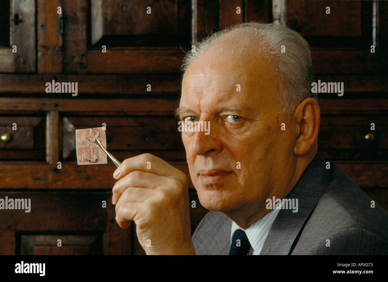 John Marriott, un collectionneur de timbres chez lui avec un groupe De 4 timbres rares années 90 précieux si tenir doucement avec Une paire de pinces UK HOMER SYKES Banque D'Images