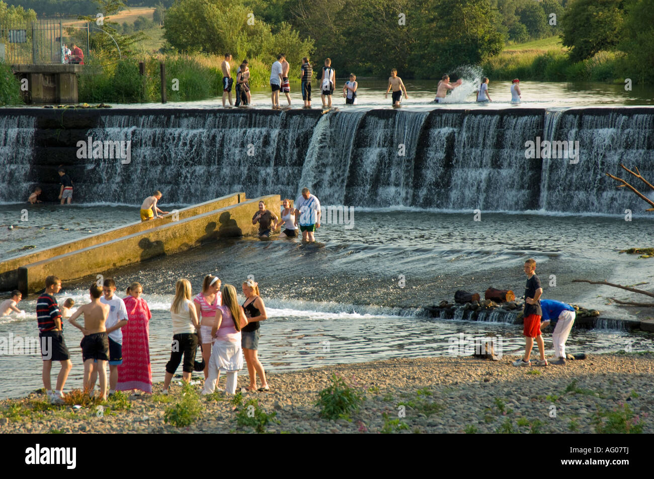 Enfants jouant au cours de l'été chaud dans la rivière à Denton Holme Weir Carlisle Cumbria UK Banque D'Images