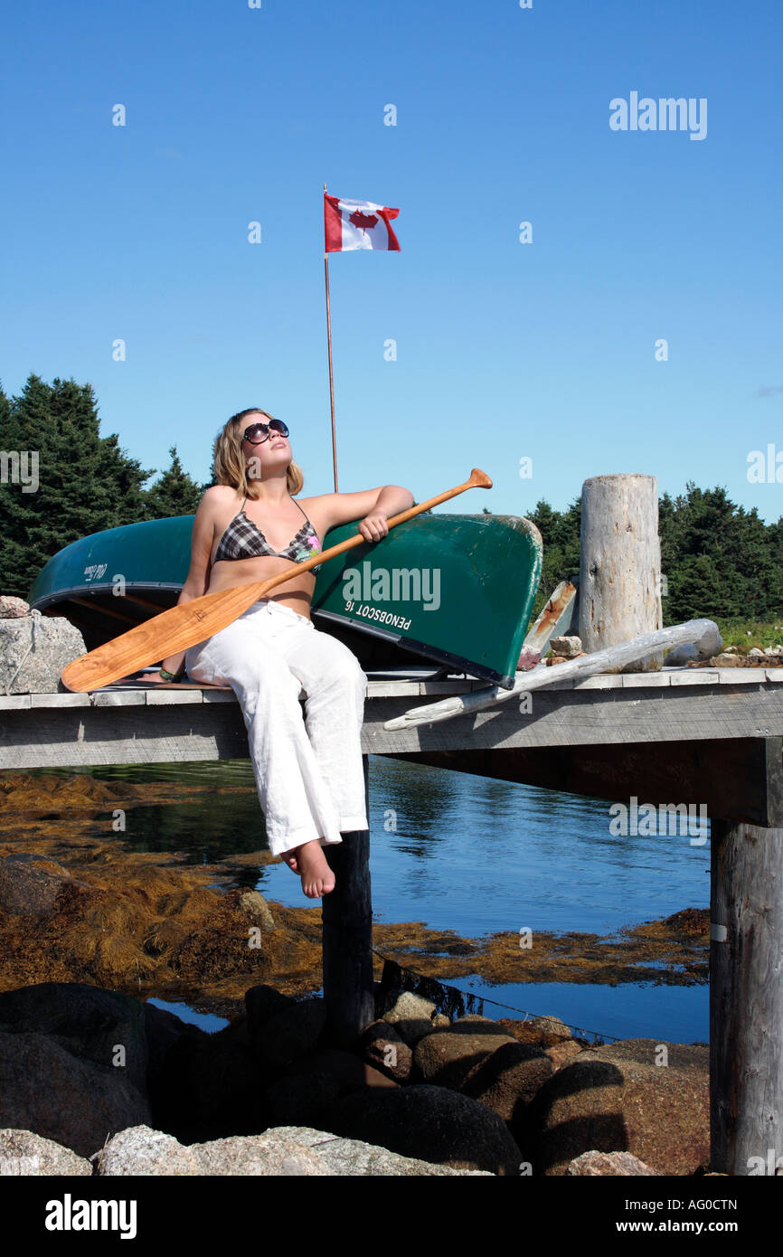 Adolescente de bronzer sur une jetée avec banc Adirondack et de la vieille ville de canoe, en Nouvelle-Écosse, Canada. Photo par Willy Matheisl Banque D'Images