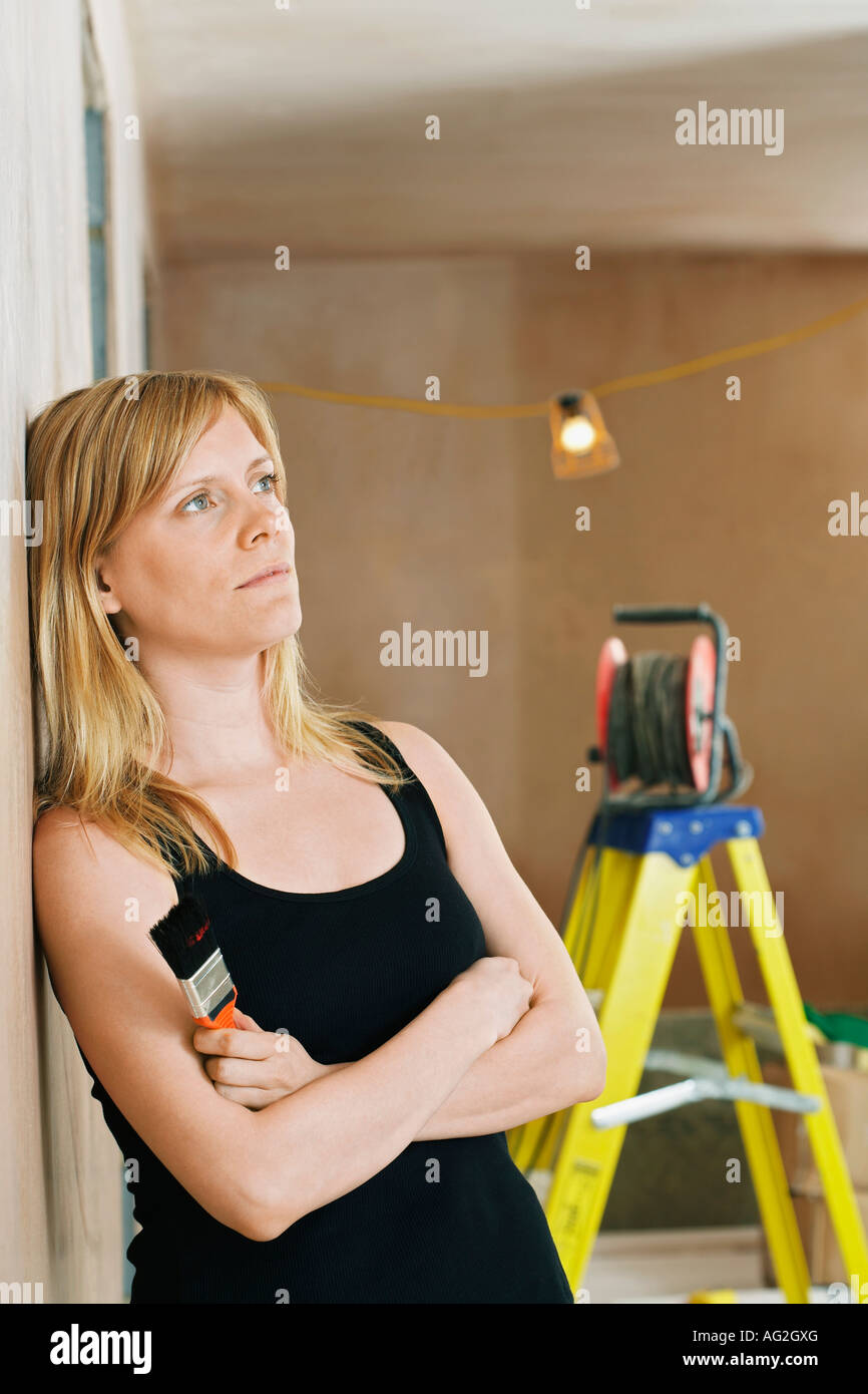 Pensive woman leaning against wall, l'échelle en arrière-plan Banque D'Images