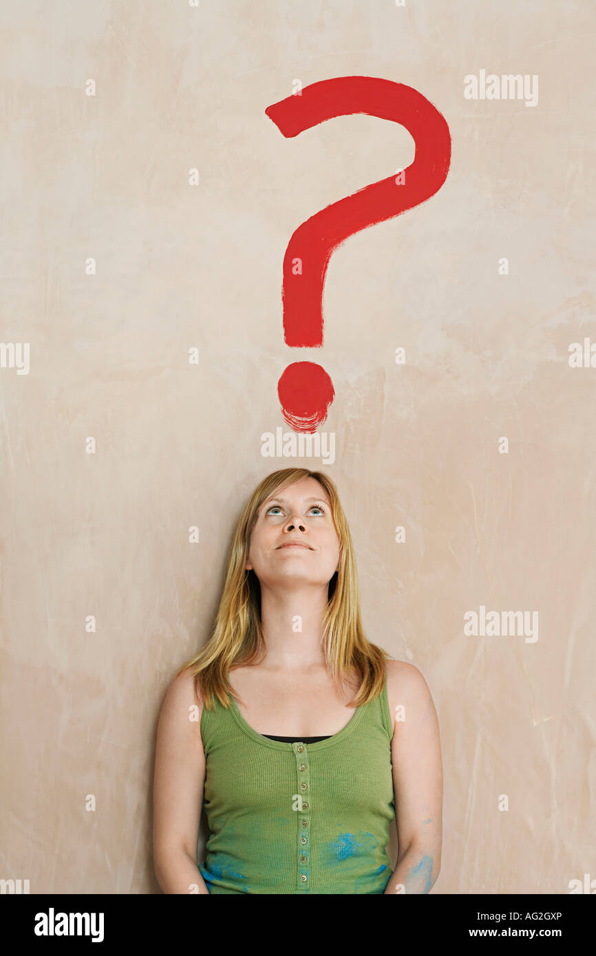 Woman leaning against wall avec point d'interrogation peint Banque D'Images