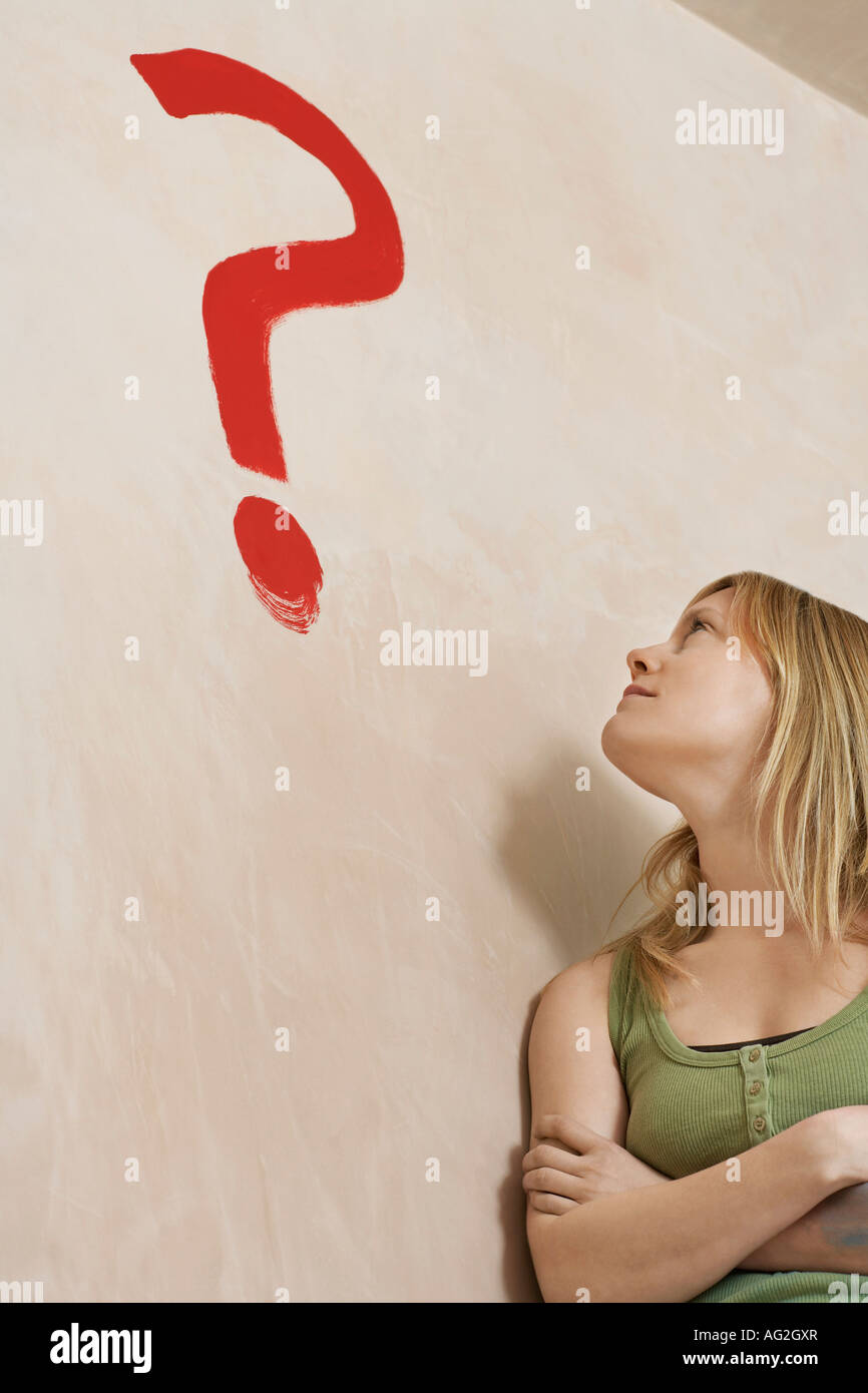 Woman leaning against wall avec point d'interrogation peint Banque D'Images
