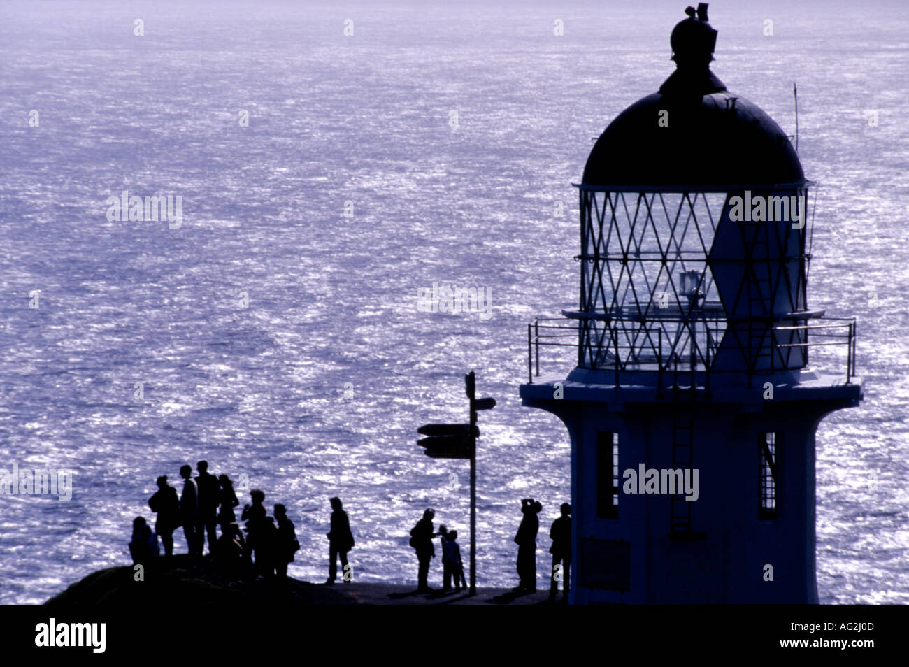 Du cap Reinga Lighthouse silhouette sur la mer de Tasman avec chiffres et signpost ci-dessous Ile du Nord Nouvelle Zélande Banque D'Images