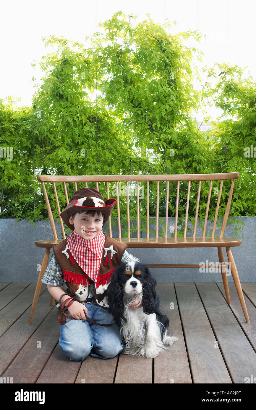 Boy (7-9) wearing cowboy costume, à genoux avec chien en bois Banque D'Images