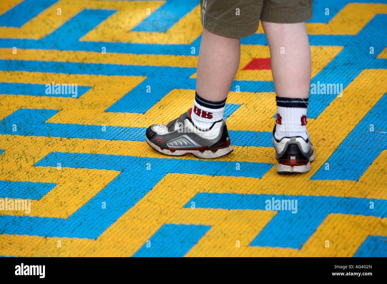 Pieds des chaussures et des bas de jeune garçon en short marche autour de  petit labyrinthe jaune et bleu mat dans un parc public Photo Stock - Alamy