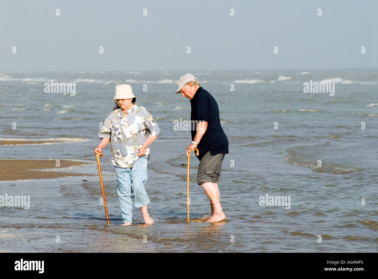 Vieux couple âgé le canotage en eau peu profonde de Camber East Sussex Côte Sud Angleterre Grande-bretagne UK EU Europe Banque D'Images