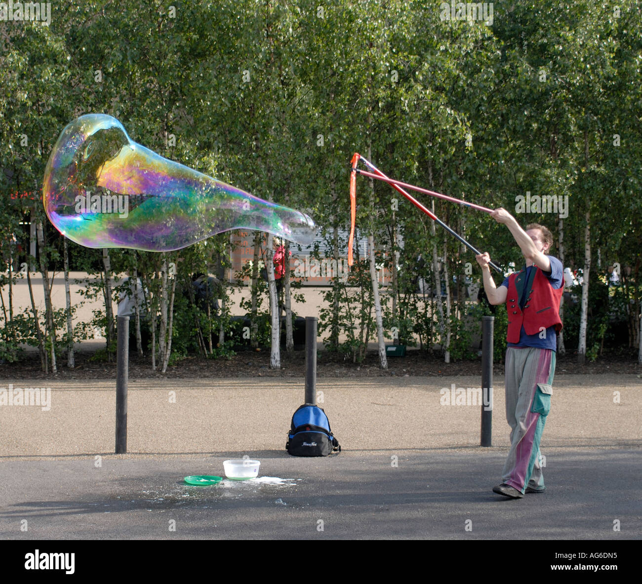 Un artiste de rue souffle des bulles de savon géantes avec les couleurs arc-en-ciel à l'extérieur de la nouvelle Tate Gallery Southwark London UK 23 Juin 2006 Banque D'Images