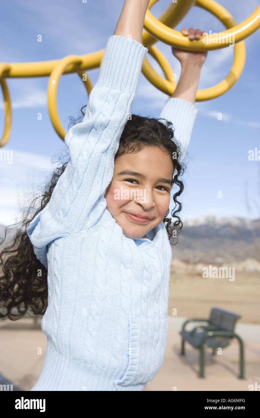 Dix ans fille se balançant sur monkey bars, d'école, l'ethnicité hispanique Banque D'Images
