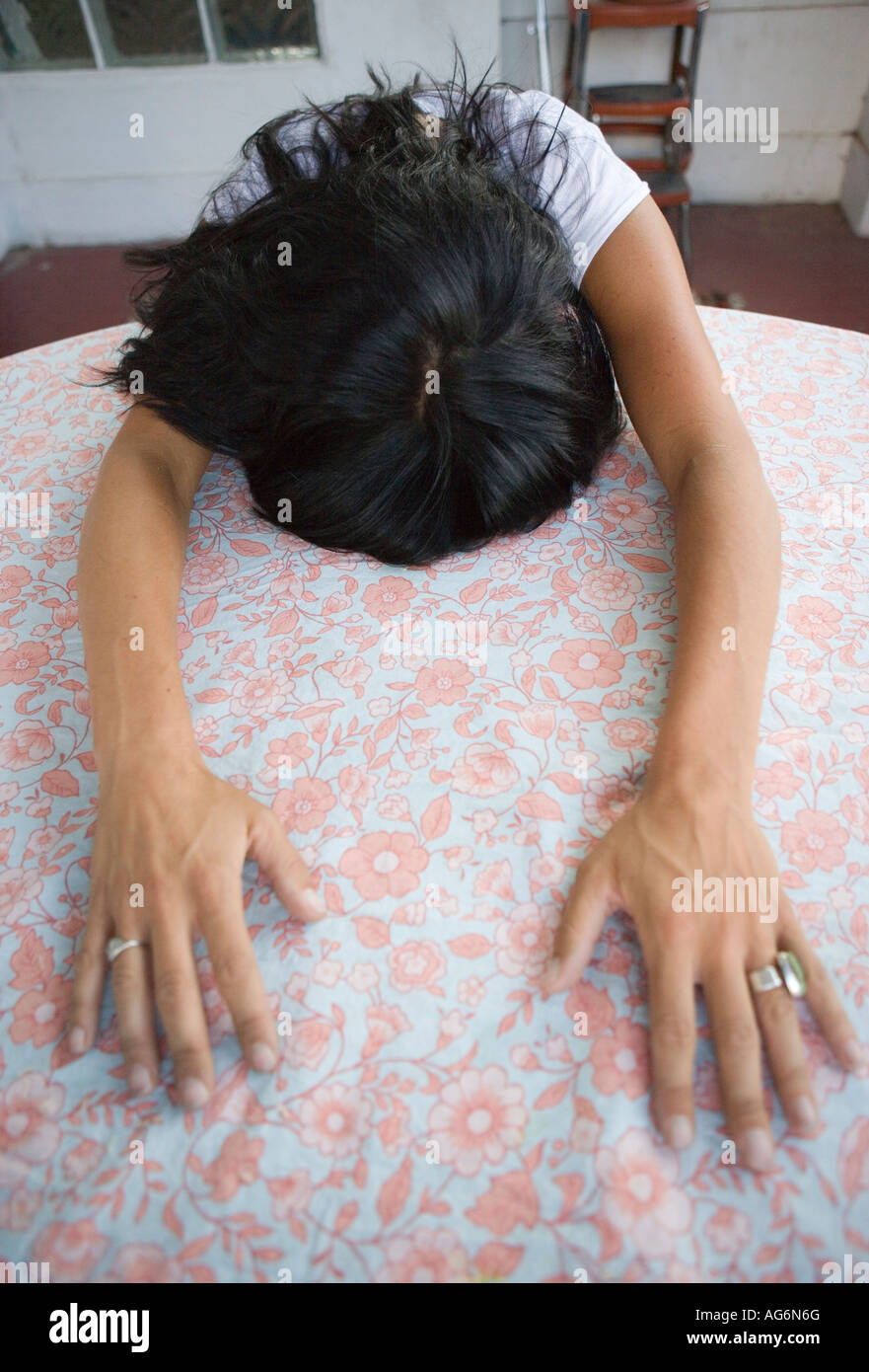 Femme avec la tête en bas et les bras tendus sur la table Banque D'Images