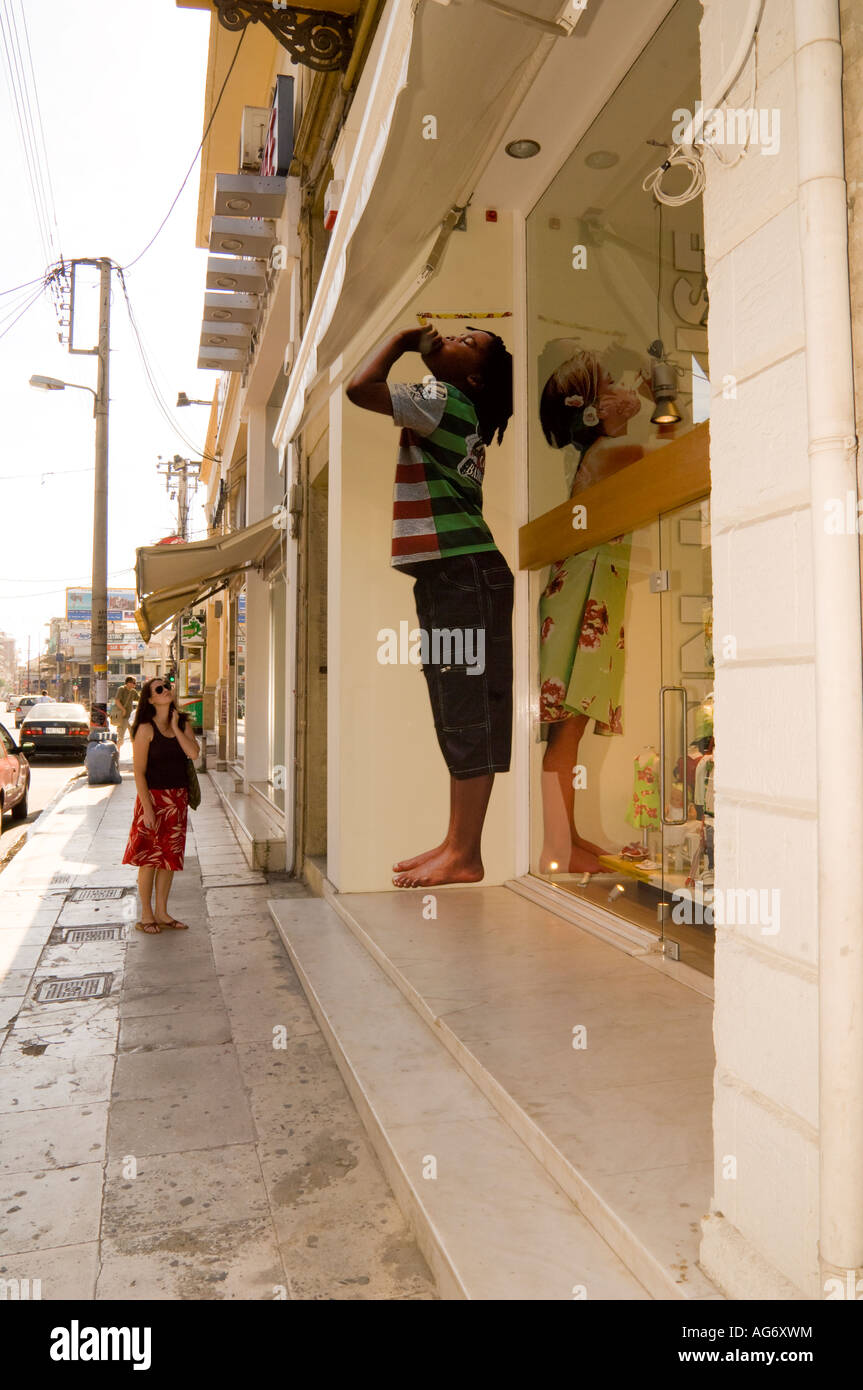 Femme regarde droit géant de jeune garçon imprimé sur le mur extérieur de l'atelier à La Canée, Crète, Grèce Banque D'Images