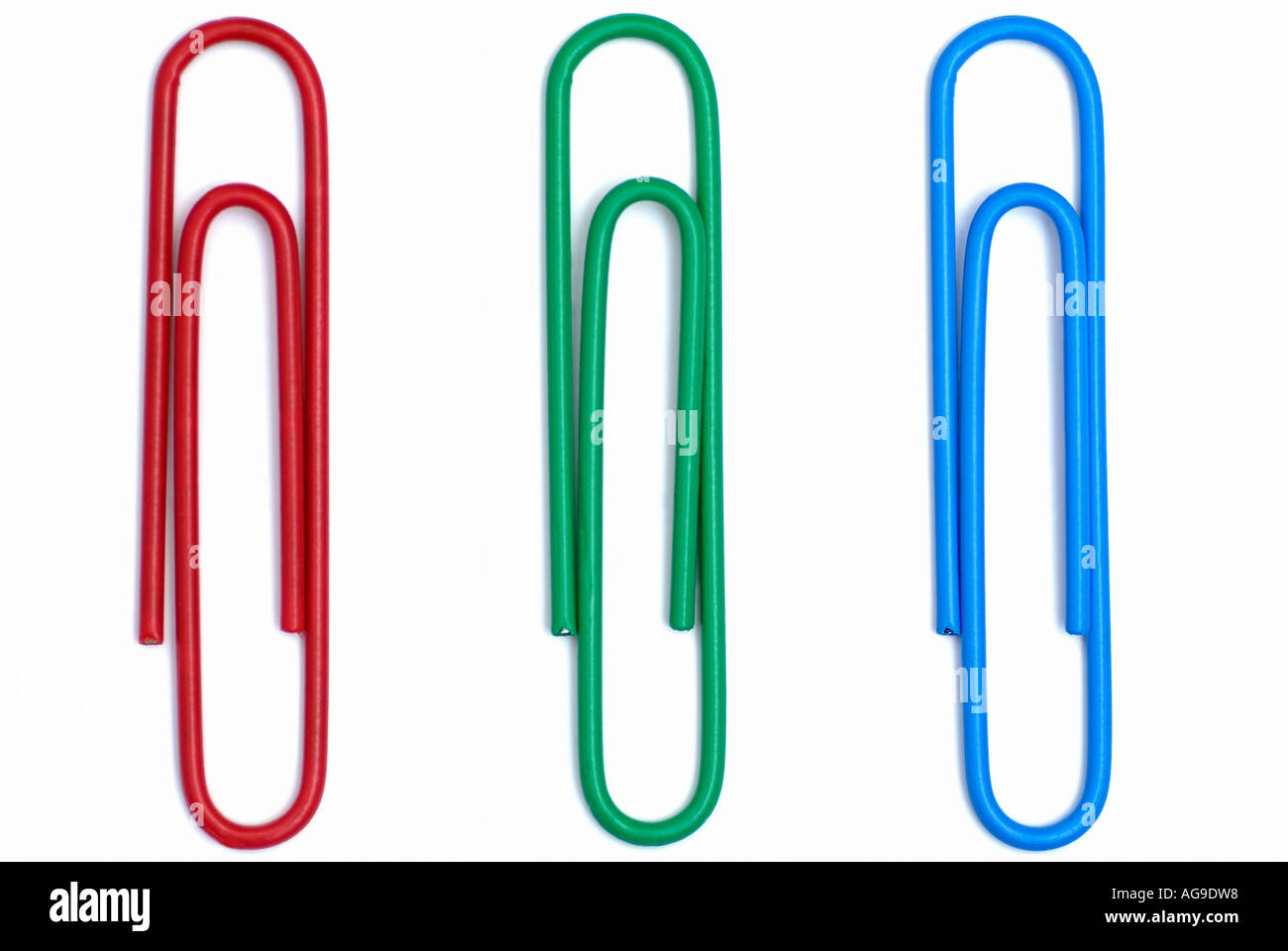 Trombones de bureau contre un fond blanc trois objets disposés comme rouge, vert et bleu Banque D'Images