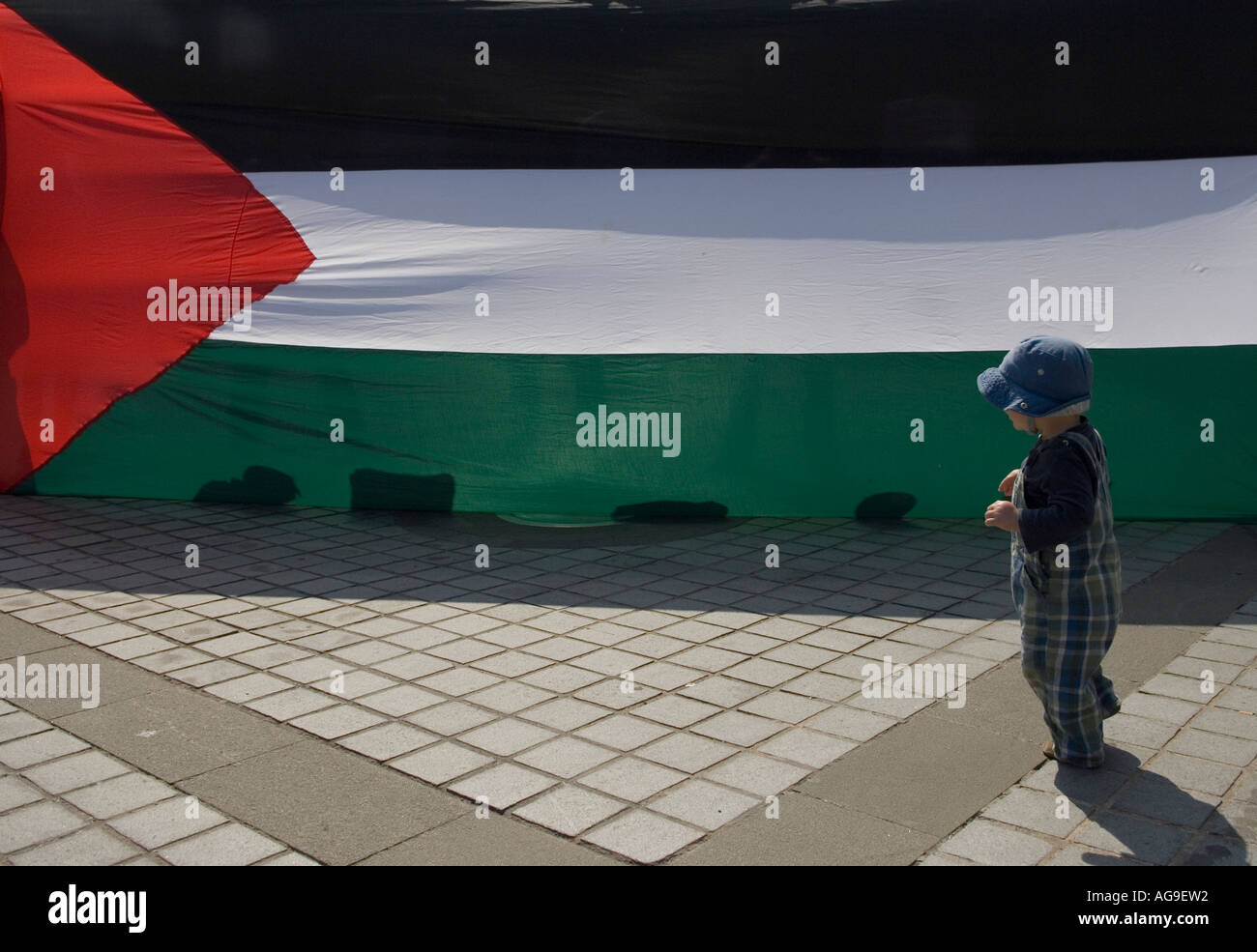 Enfant curieux regardant un énorme drapeau palestinien Banque D'Images