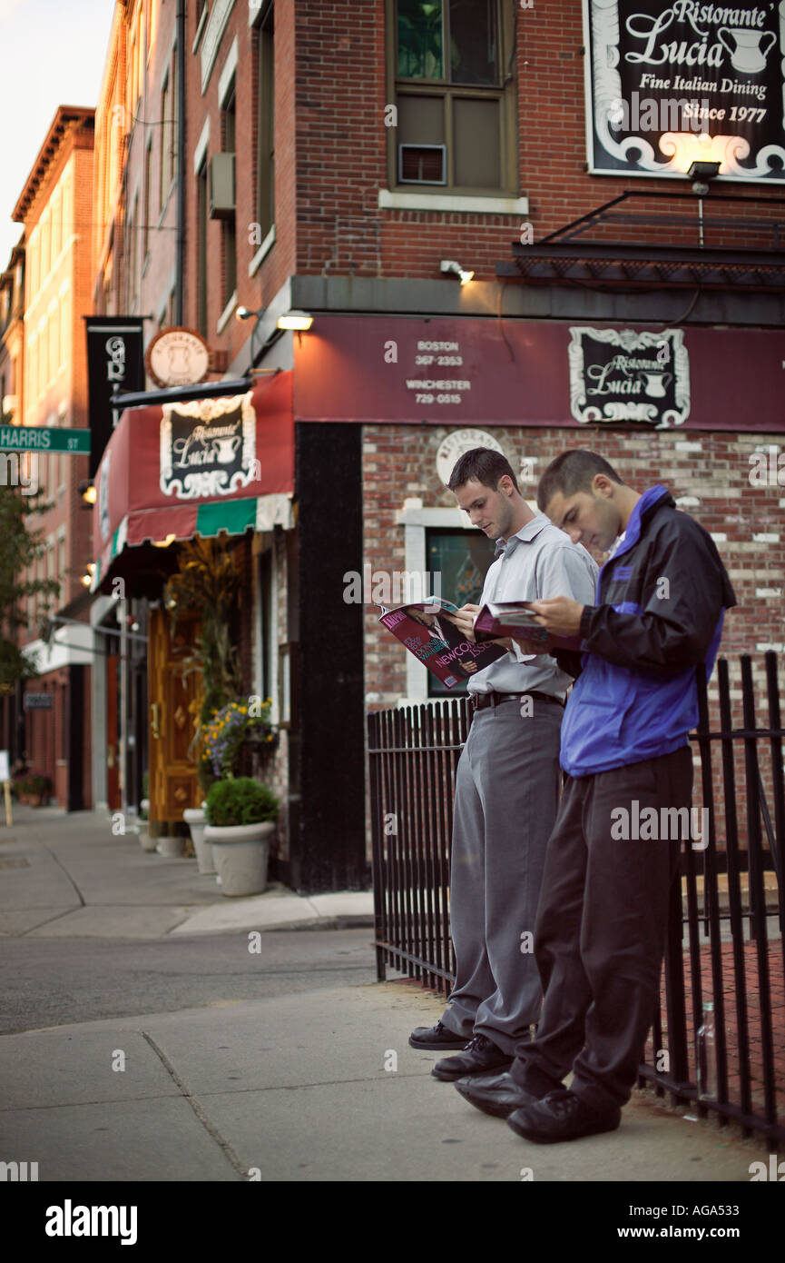 Deux hommes tuer le temps lire des magazines, tout en travaillant comme valets de parking restaurant à proximité sur Hanover Street district Italien Banque D'Images