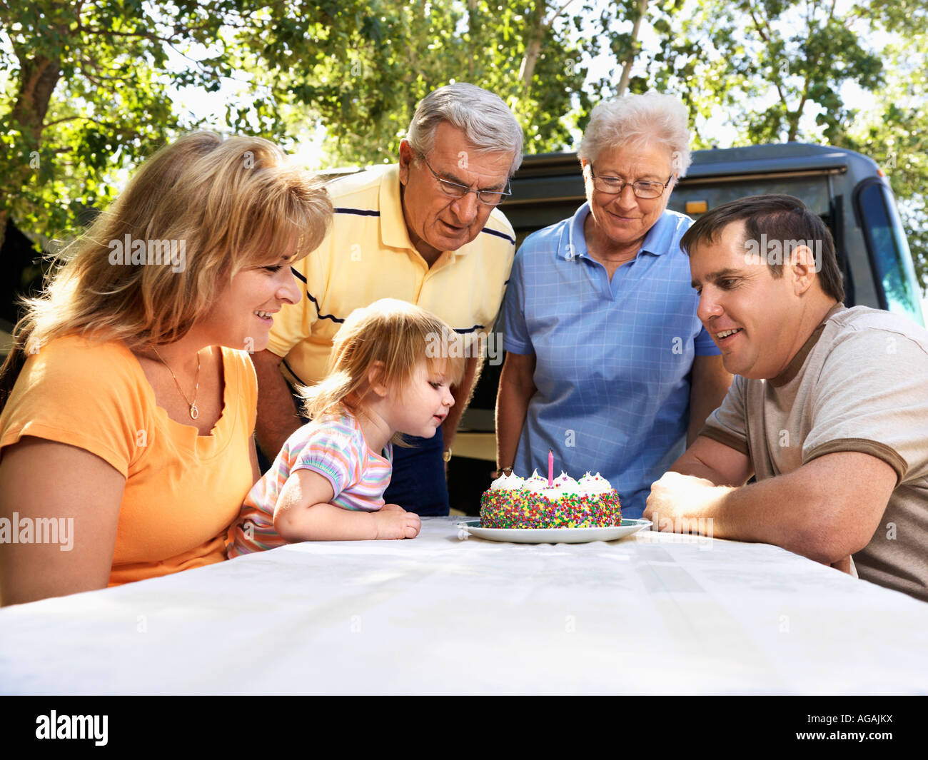 Trois générations de la famille caucasienne assis à table de pique-nique célébration d'anniversaire de childs femelle avec gâteau Banque D'Images