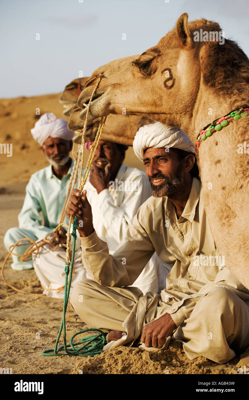 Chameaux avec leurs propriétaires assis en face d'eux un grand désert du Thar à l'extérieur de l'Inde Rajasthan Jaisalmer modèles sortis Banque D'Images