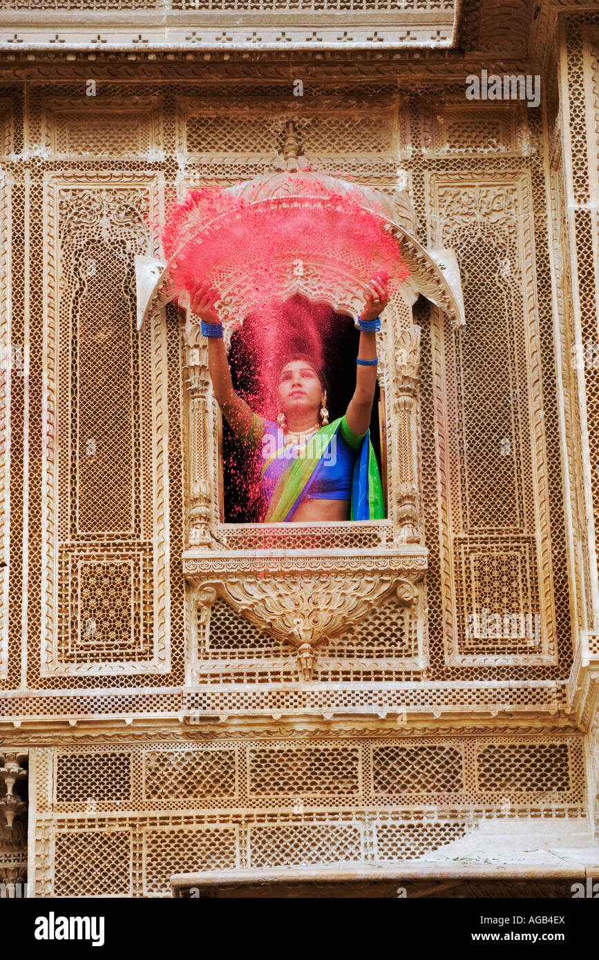 Woman throwing holi aux couleurs vives grâce à la poudre une fenêtre d'un haveli Banque D'Images