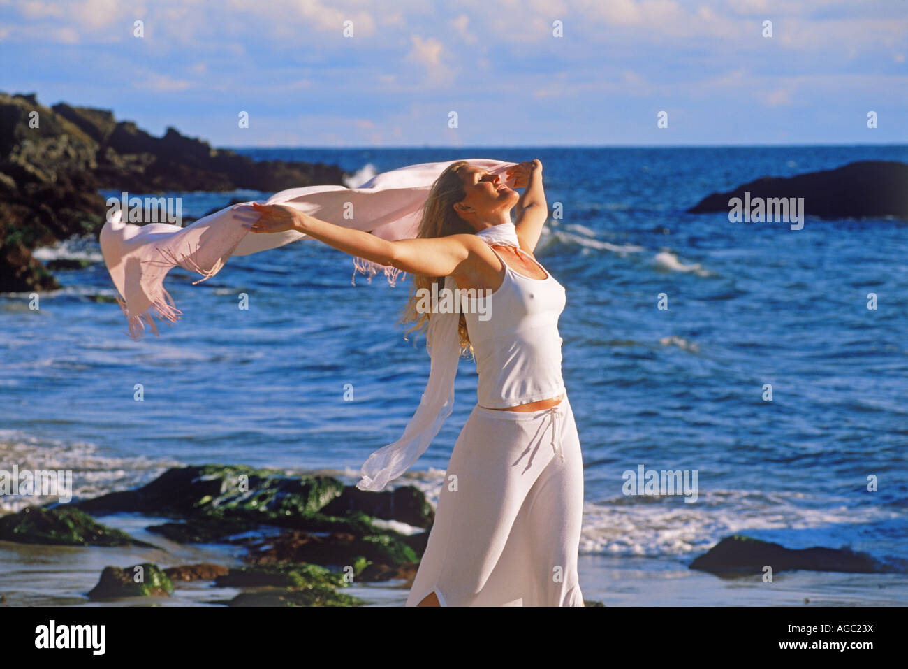 Femme en robe blanche et un châle se sentir libre et heureux sous un ciel ensoleillé de sable sur la côte de Californie Banque D'Images