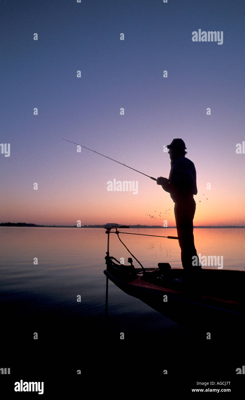 Pêche basse silhouette Lever coucher fisherman holding rod ciel bleu Banque D'Images