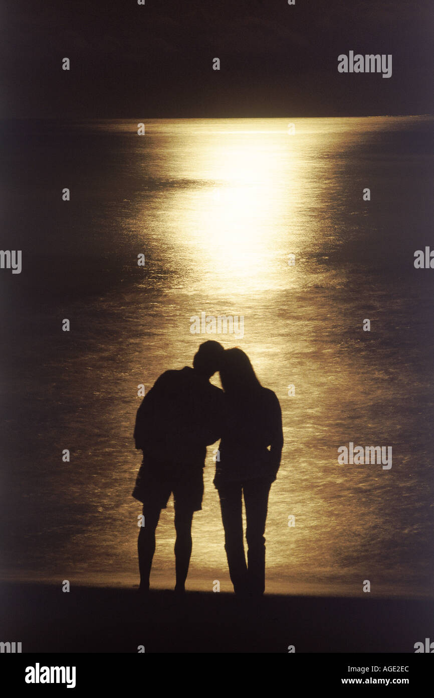 Couple on shore se profilant dans moonlight romantique Banque D'Images