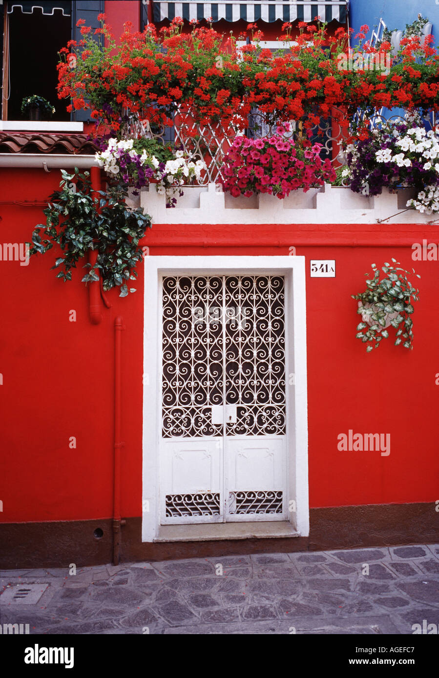 Suppression porte blanche situé dans un mur rouge vif sur l'île colorée de Burano Italie Banque D'Images