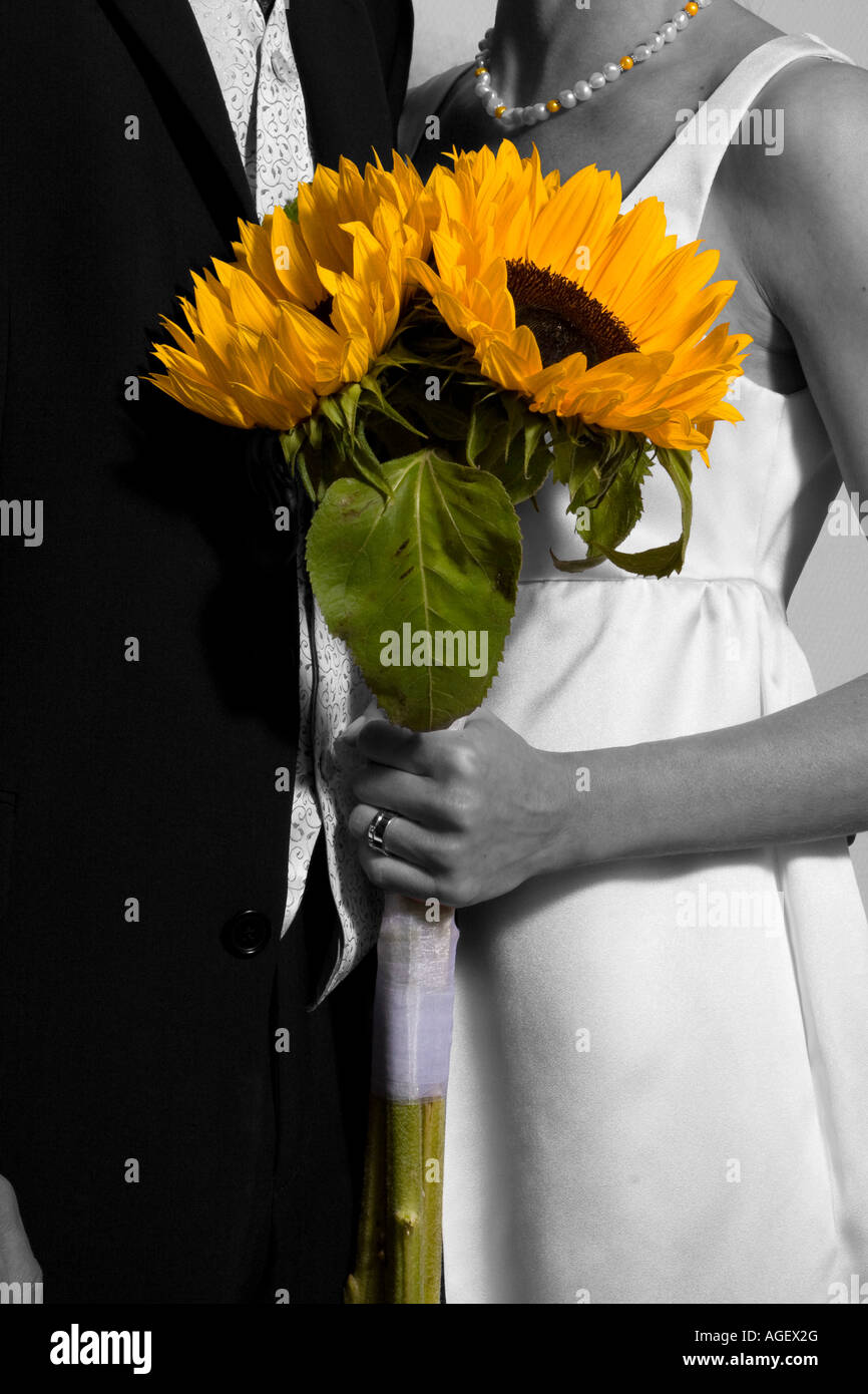 Une image en noir et blanc d'un couple de mariage avec une couleur de tenue de tournesol en face d'eux. Banque D'Images