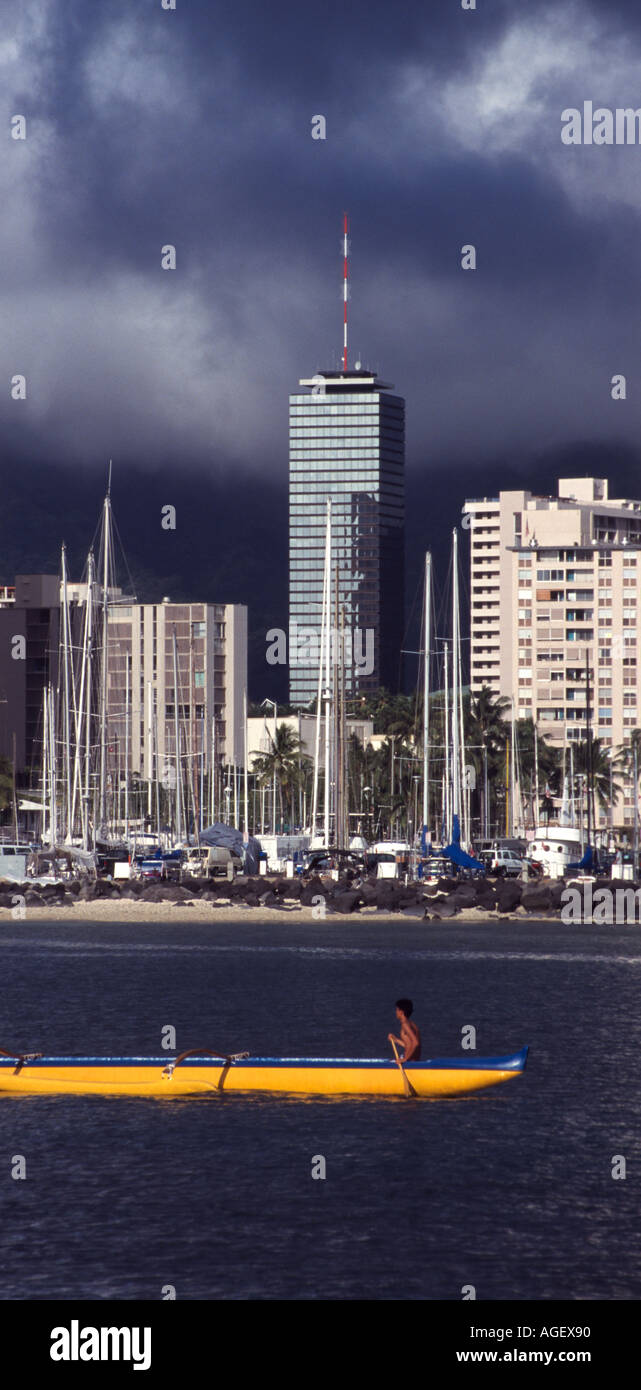 High school équipe pirogue pratiquant au canal Ala Wai avec un bâtiment de tempête sur les collines Banque D'Images