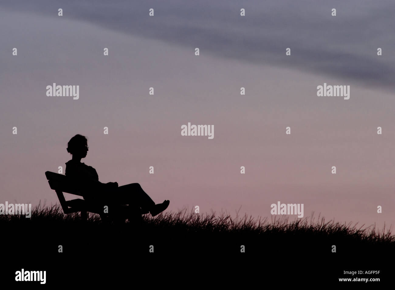 Femme sur banc de parc au crépuscule. La colline du Parlement, Hampstead Heath, Londres, Angleterre Banque D'Images