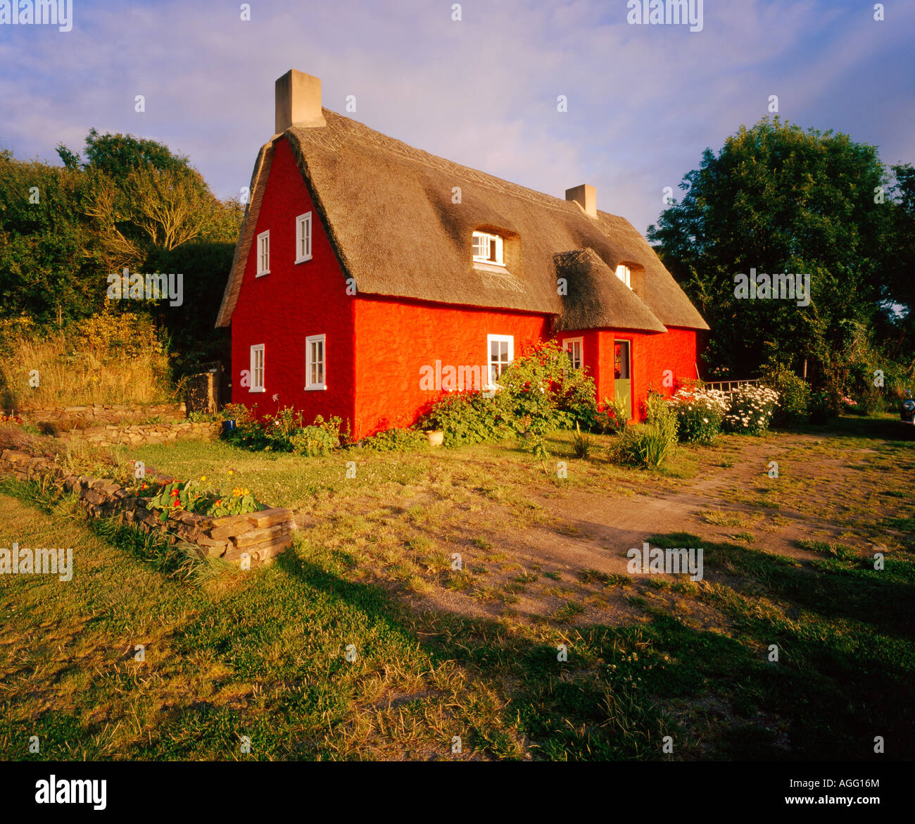 Un cottage peint rouge avec un toit de chaume dans un milieu rural à la campagne Banque D'Images