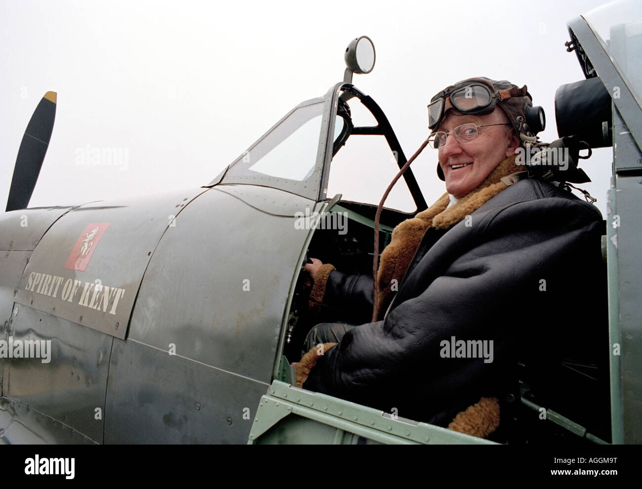 Homme assis dans un véritable avion Spitfire de la seconde guerre mondiale, le port de la veste de vol original, un chapeau et des lunettes. Banque D'Images