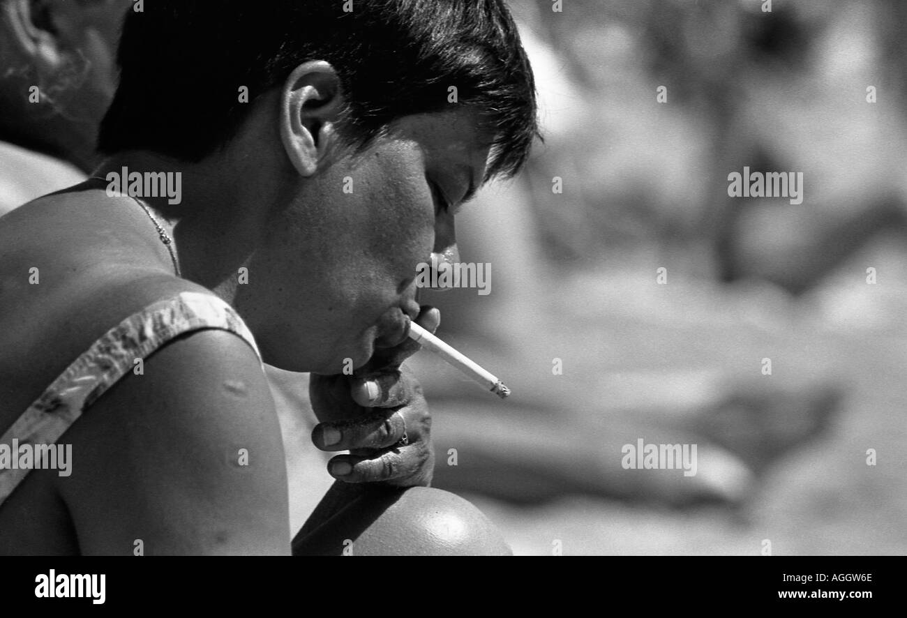 Femme fumant une cigarette sur la plage de Magalluf Majorque Banque D'Images