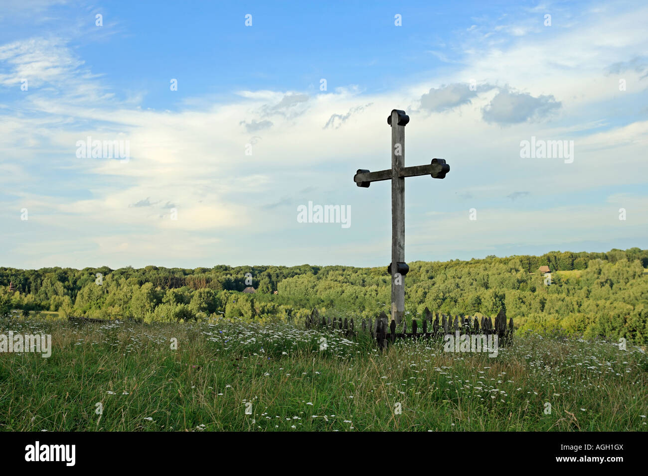 La croix en bois chrétienne sur l'herbe envahi par la forêt et colline colonie loin Banque D'Images