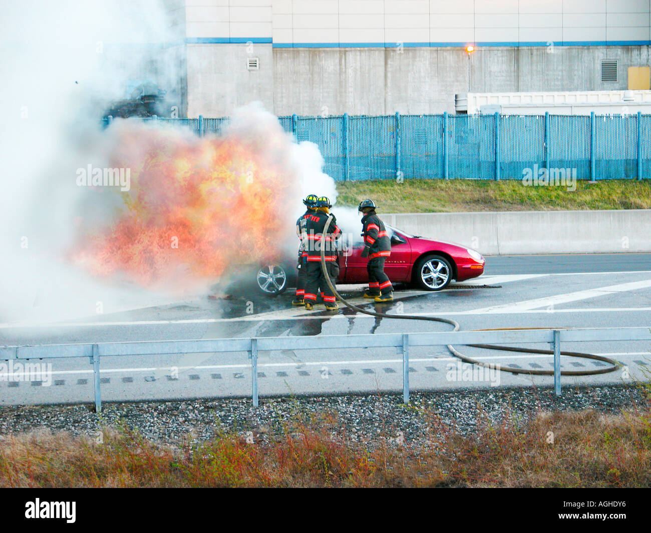 Les pompiers éteindre les feux d'une voiture sur l'autoroute Banque D'Images