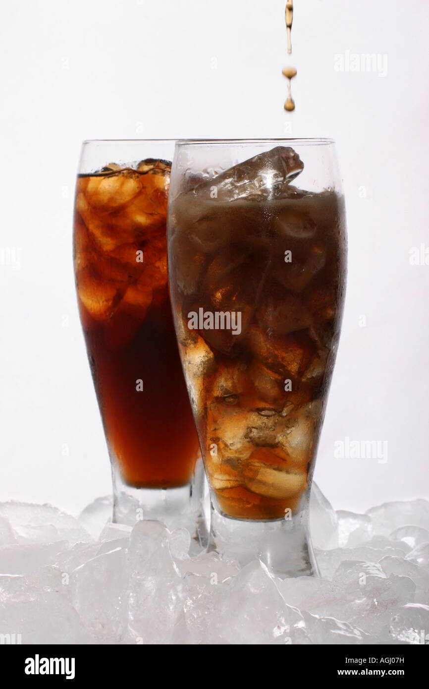 Verser une boisson Coca-Cola dans un verre avec des glaçons sur fond de table blanc Coca-Cola Drink personne de marque verticale ne boit de boissons gazeuses haute résolution Banque D'Images