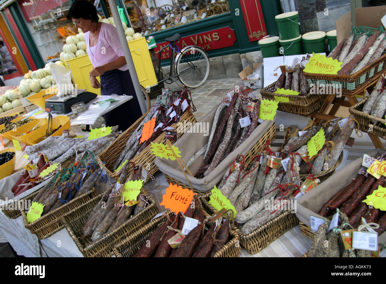 Femme propriétaire sur market stall dans Briquobec Normandie France vente de salami et d'autres charcuteries Banque D'Images