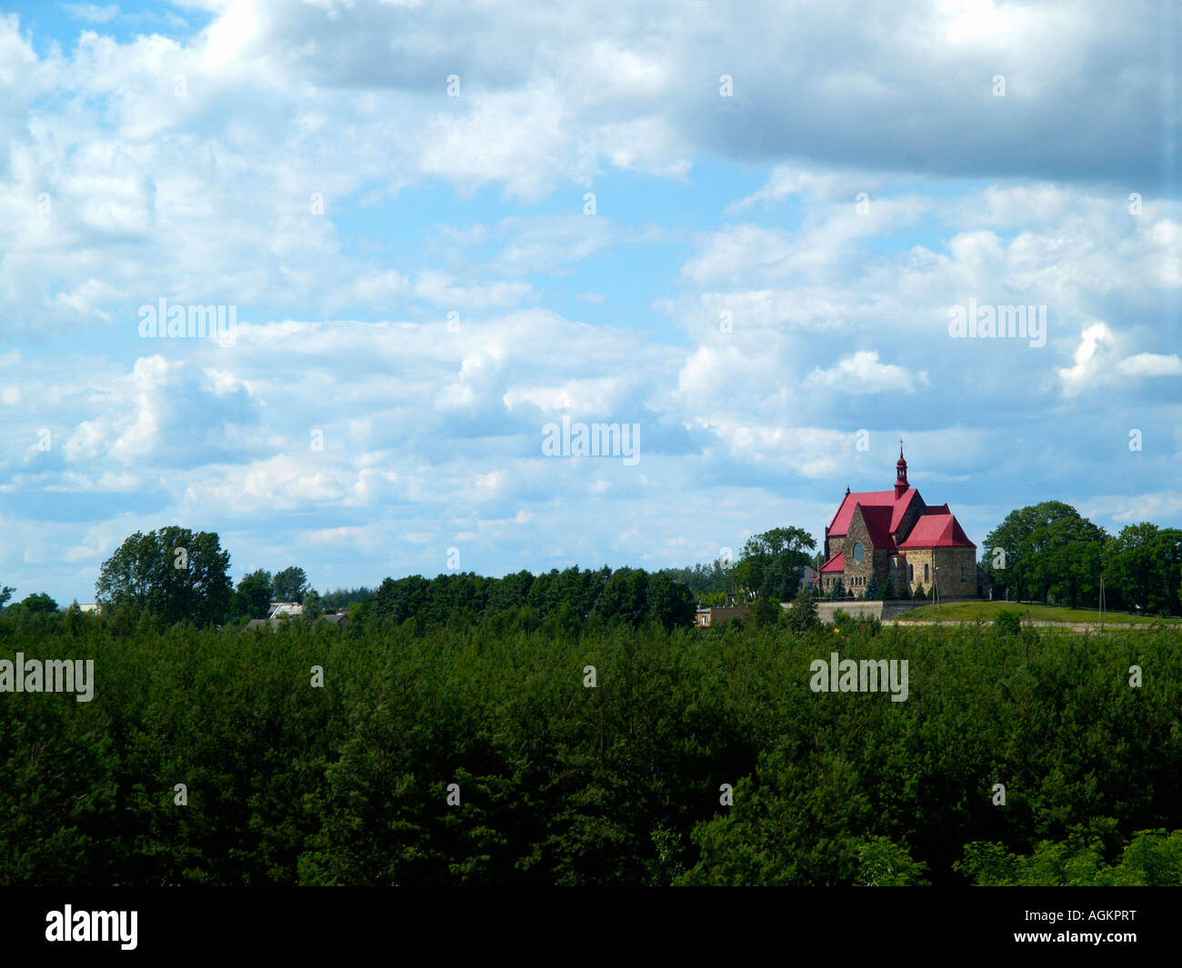 L'église au toit rouge dans la campagne polonaise au milieu de l'été avec ciel bleu et nuages fluffly frais généraux. Banque D'Images