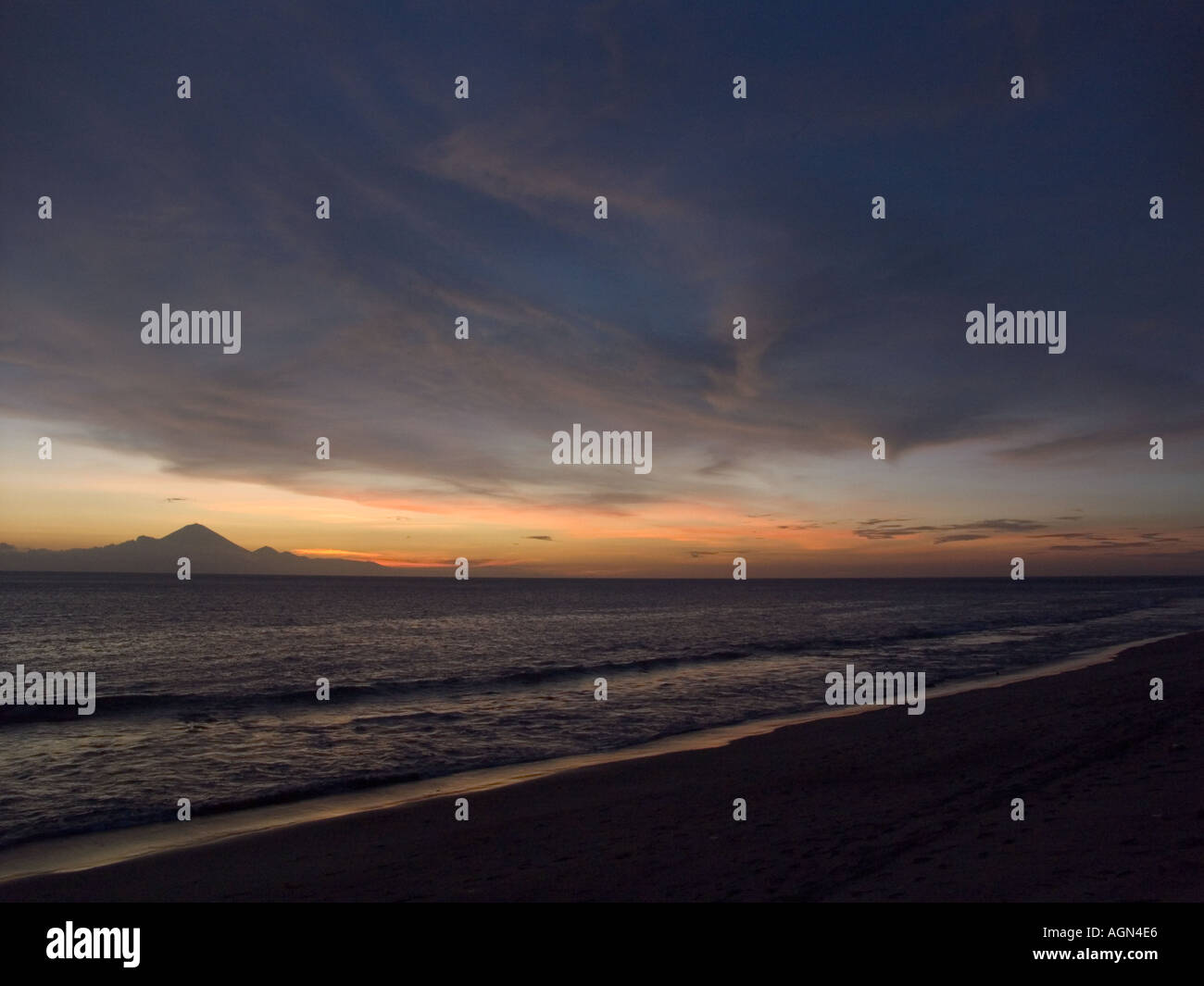 Le soleil tombant au-dessous de l'horizon avec Bali et le Mont Agung en arrière-plan vu de Mangsit Senggigi Beach Lombok en Indonésie Banque D'Images