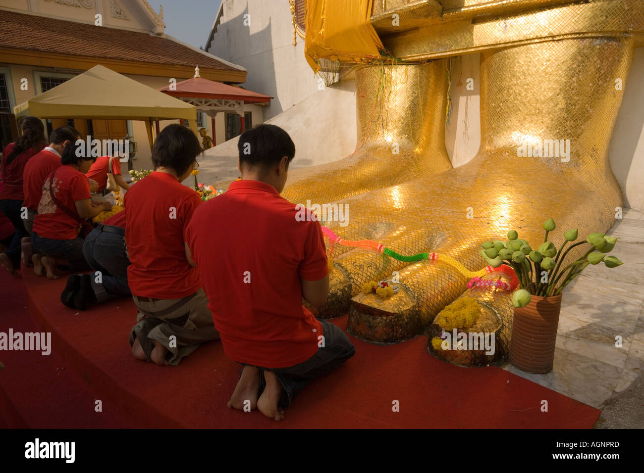 Les gens priant devant la statue de Bouddha doré de 32 m de haut Wat Intharawihan Bangkok Thaïlande Banglamphu Banque D'Images