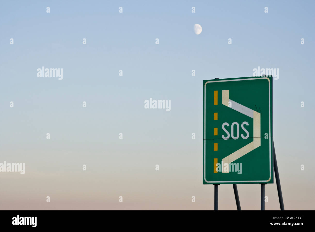 Green signe de la circulation sur une voie publique avec l'inscription SOS indiquant un espace de stationnement ou d'urgence auxiliaire, la lune dans le backg. Banque D'Images