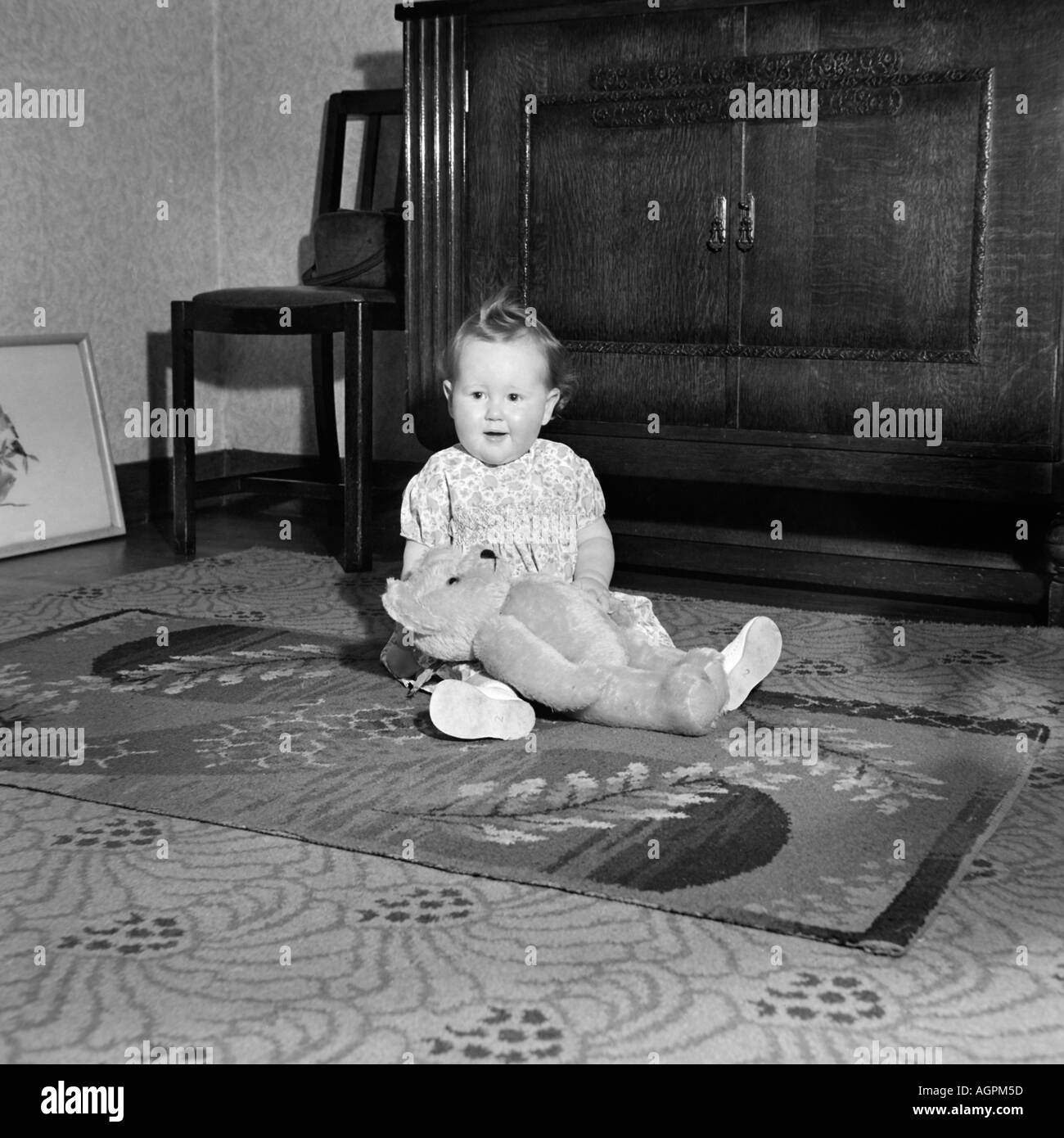 OLD VINTAGE SNAPSHOT FAMILLE PHOTOGRAPHIE DE BABY GIRL PLAYING WITH TEDDY BEAR SUR TAPIS DE SALON Banque D'Images